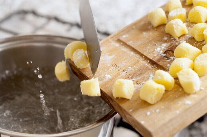A person cutting gnocchi on a wooden board. 3