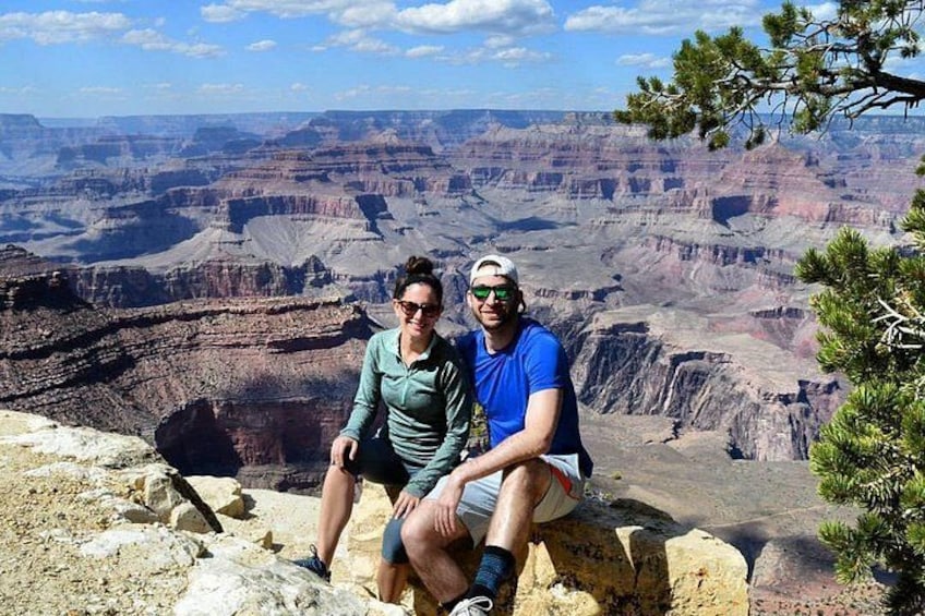 Two people sitting on a rock with a view of the Grand Canyon. 1