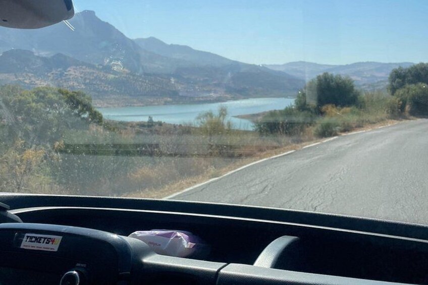Una carretera con un lago y montañas al fondo. 3