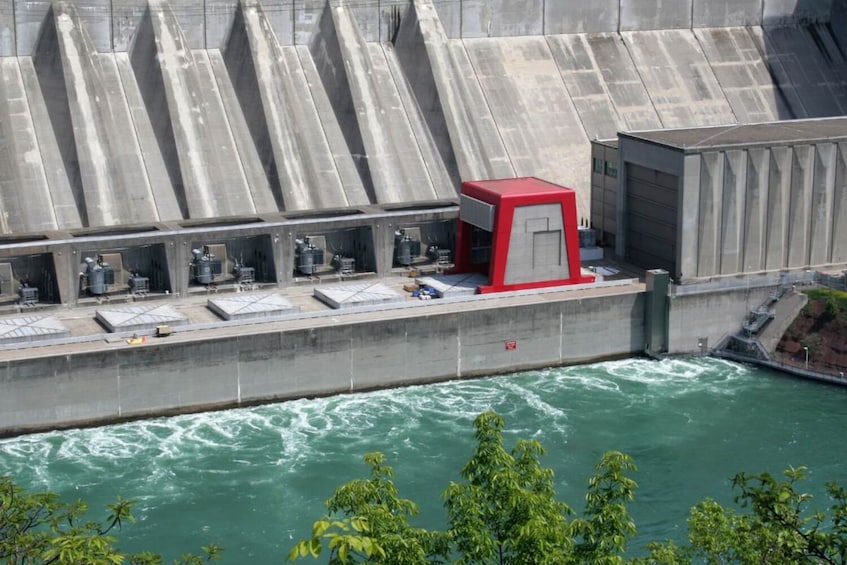 A dam with multiple spillways and a red control building. 5