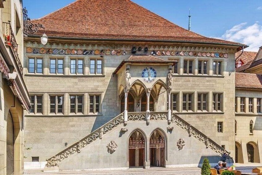 A historic building with a clock tower, ornate facade, and a staircase leading to an entrance. 3