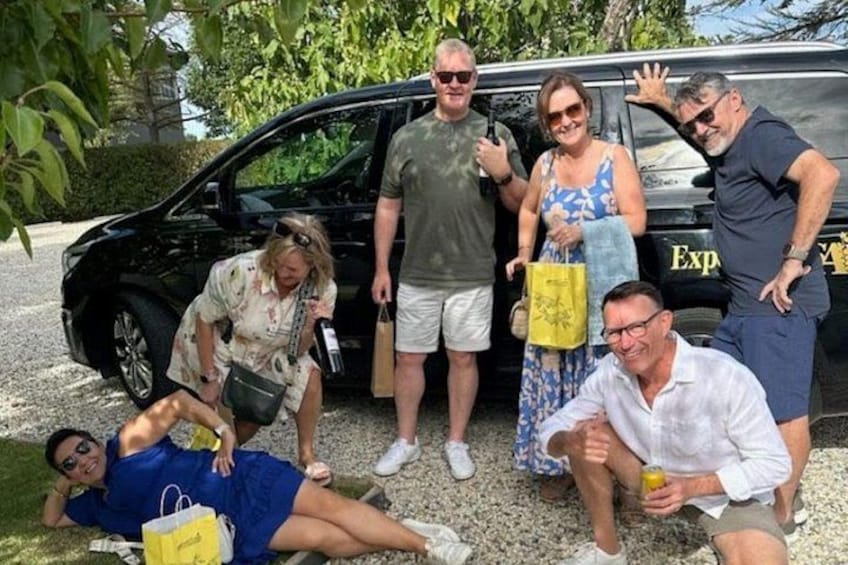 Eine Gruppe von Personen posiert vor einem schwarzen Fahrzeug, auf dessen Seite das Wort 'Exp' zu sehen ist. 2