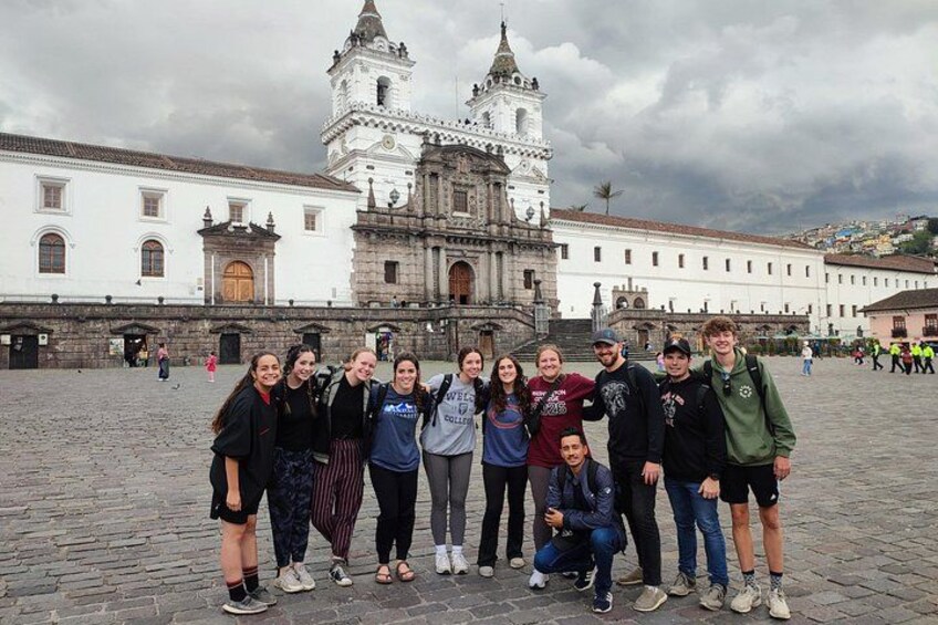 Een groep mensen poseren voor een historisch gebouw met twee opvallende torens. 1