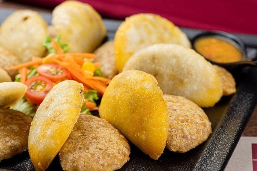 Een bord met gefrituurde snacks, mogelijk frituursnacks, met een portie gesneden groenten en dipsaus. 4