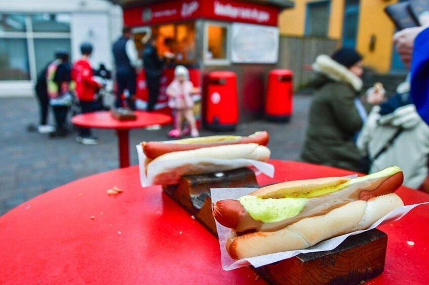 To hotdogs på et rødt bord med sennep og ketchup. 3