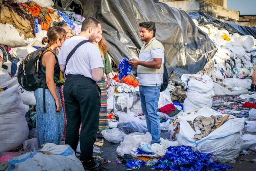 Eine Gruppe von Menschen steht inmitten großer Müllhaufen und weggeworfenen Gegenständen. 4