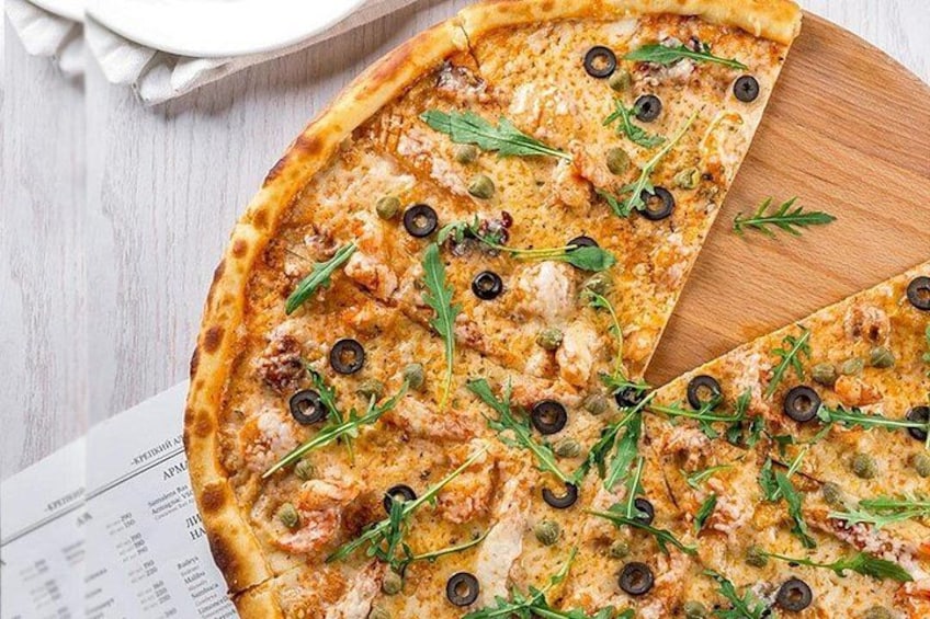 Pizza belegd met toppings op een houten plank. 4