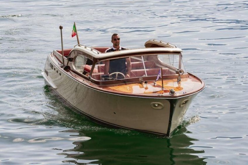 A vintage boat with a flag, moving through calm water. 4