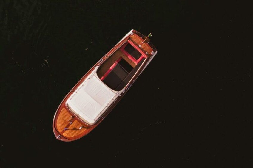 Een bootje met een wit interieur en een rood dakzeil, drijvend op het water. 2