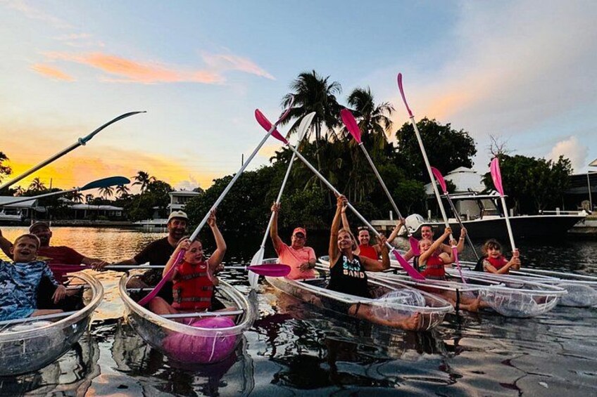 A group of people in canoes on a calm body of water, with a sunset in the background. 5