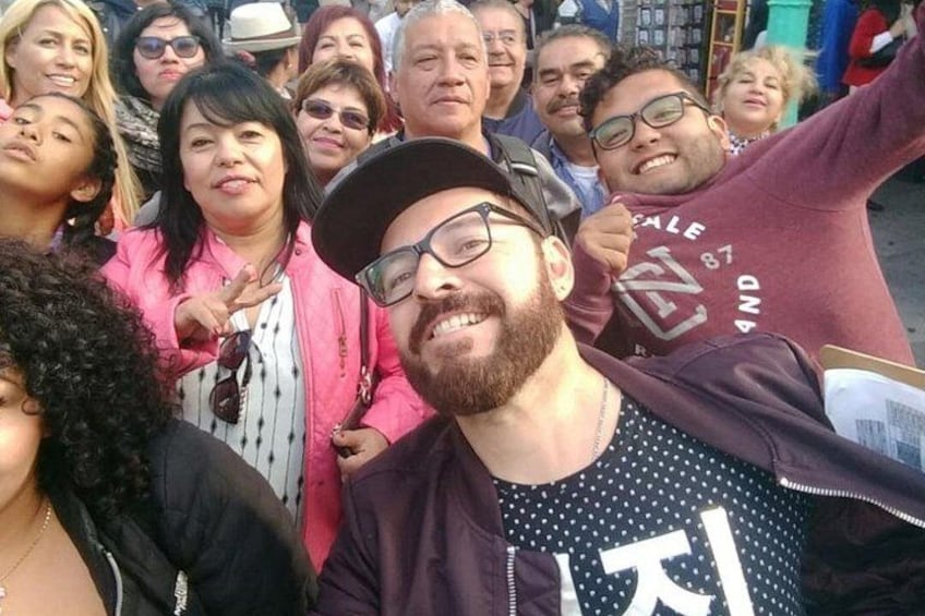 A group of people outdoors, some wearing jackets, with a person in the foreground wearing a polka dot shirt. 3