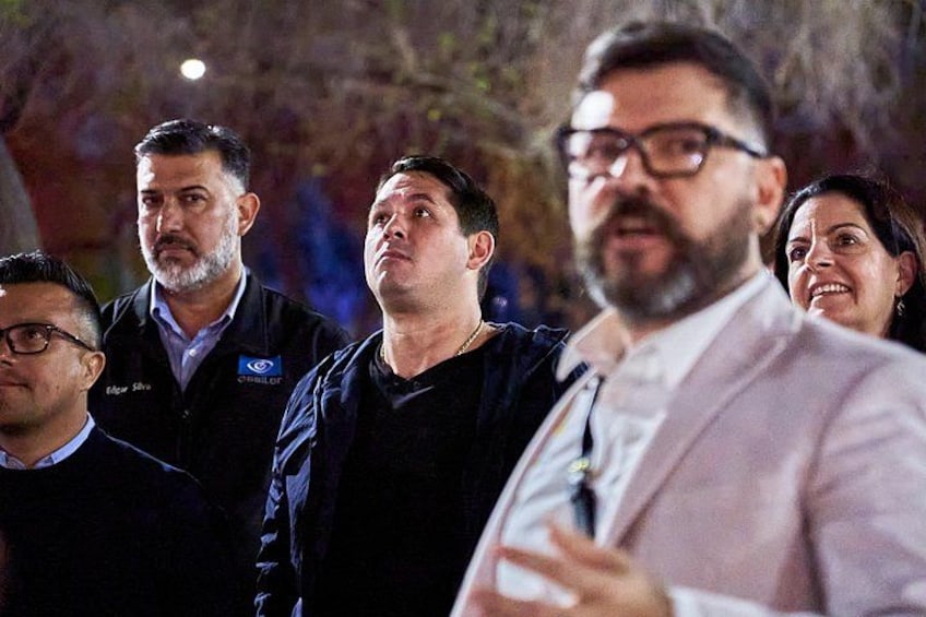 A group of people standing outdoors at night. 5