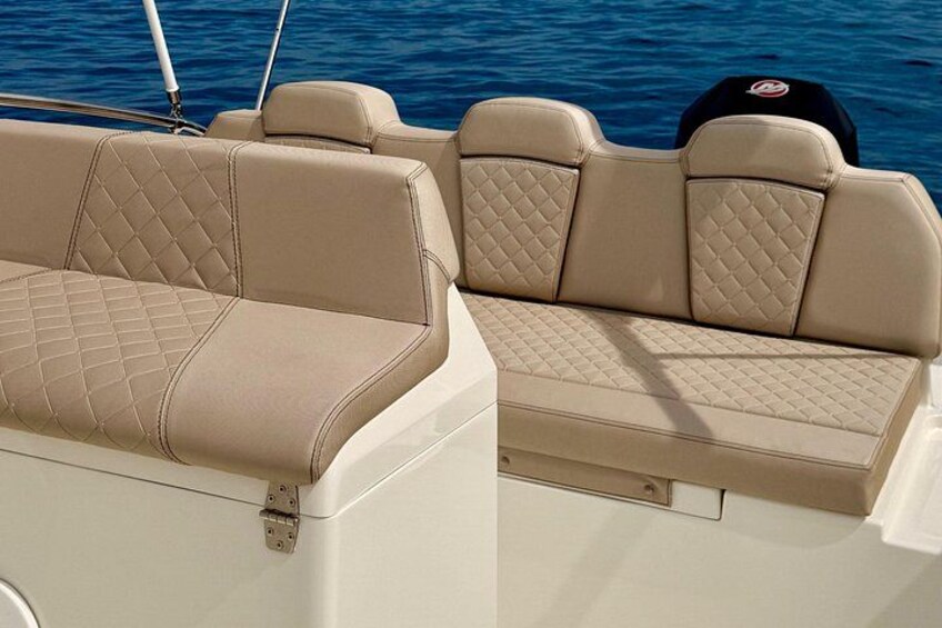 A boat's interior with beige cushioned seating and a white exterior. 2