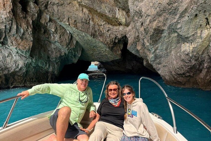 A boat with three people near a rocky cave entrance. 5