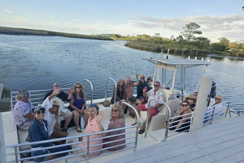 A group of people on a boat with calm water and a shoreline in the background. 1