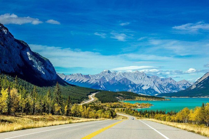 A road leading to a turquoise lake surrounded by mountains. 2