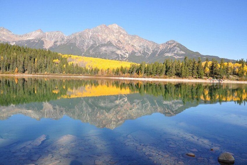 A calm lake reflecting mountains and autumn-colored trees. 4