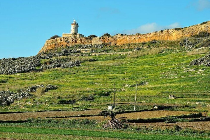 A lighthouse on a hill, terraced fields, and a clear sky. 5