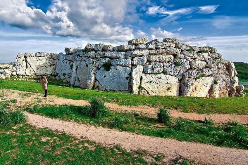 Un muro de piedra con una persona caminando cerca. 2