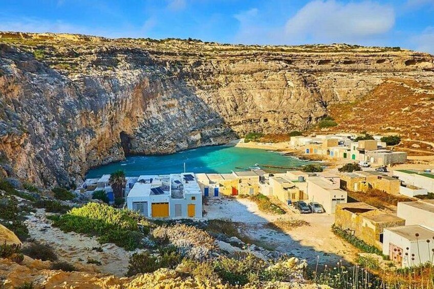 Un pueblo costero con edificios, un acantilado rocoso y una bahía turquesa. 5