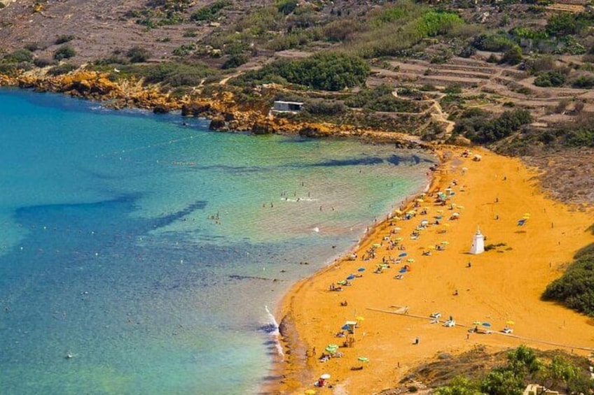 A coastal landscape with a sandy beach, clear blue waters, and rocky terrain. 4
