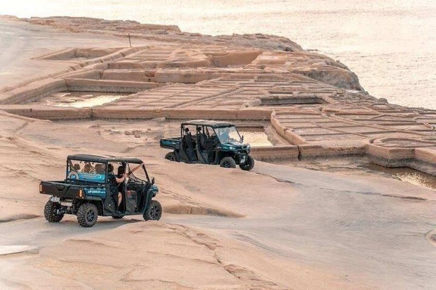 Two off-road vehicles on a rocky terrain with layered stone formations. 1