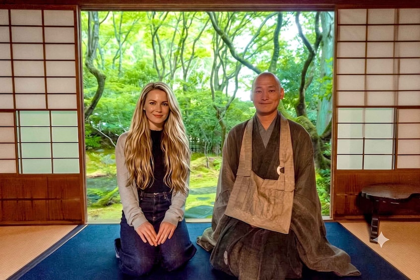 Dos personas sentadas en una habitación japonesa tradicional con suelo de tatami y vistas a un bosque verde exuberante. 1