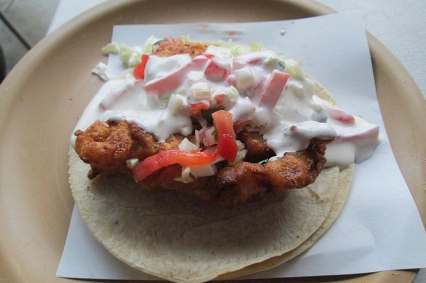 Un panino con pollo fritto, lattuga, pomodori e salsa cremosa su un piatto di carta. 5