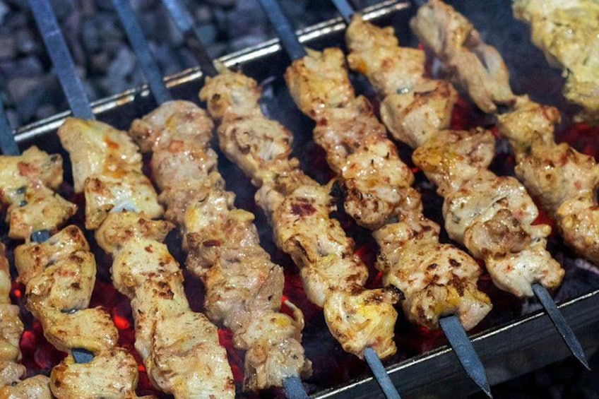 Fleischspieße werden auf einem Grill zubereitet. 3