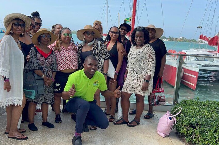 A group of people posing on a dock near a boat. 4