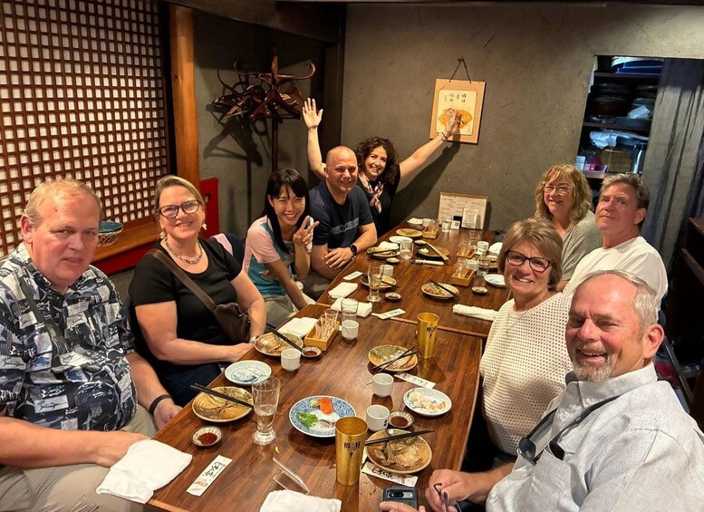 Un gruppo di persone cena in un ristorante con un tavolo di legno, diversi piatti e un menu appeso al muro. 5