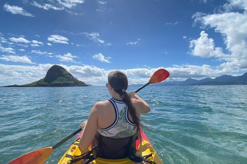 A person kayaking on a calm sea with a small island in the background. 4