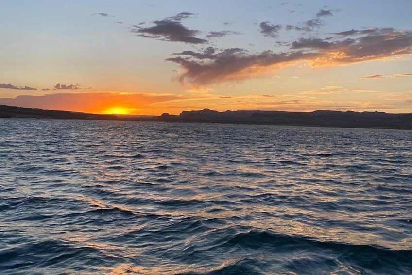 A sunset over a body of water with waves and distant landforms. 3