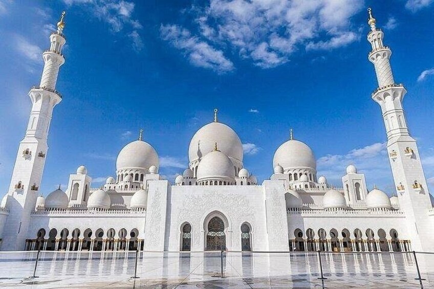Una gran mezquita blanca con cúpulas y minaretes bajo un cielo azul despejado. 1