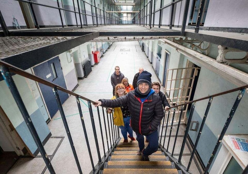 A group of people descending a metal staircase in a building with a high ceiling and large windows. 2
