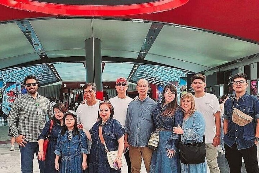 Un grupo de personas frente a un edificio moderno con techo rojo y paneles de vidrio. 2