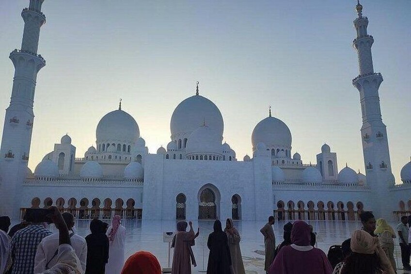 Une grande mosquée blanche, dotée de plusieurs coupoles et minarets, entourée d’une foule de personnes. 4