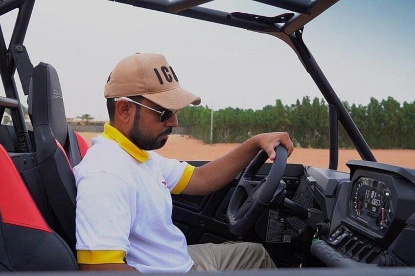 A person driving a golf cart on a dirt path with sparse vegetation. 4