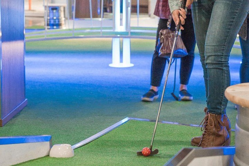 Une personne jouant au croquet sur un terrain synthétique avec une balle et un maillet de croquet. 1