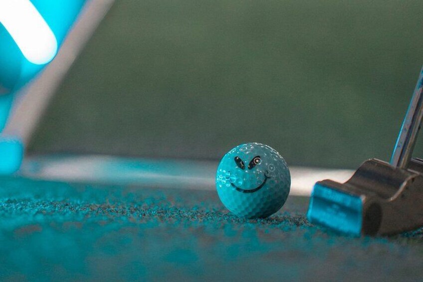 Une balle de golf avec un visage souriant, posée sur une surface verte. 4