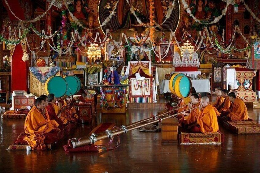 Monks in traditional robes playing musical instruments in a richly decorated temple. 5