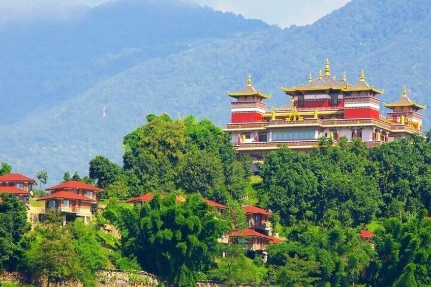 A traditional multi-tiered temple with red and gold accents, surrounded by lush green trees and mountains in the background. 4