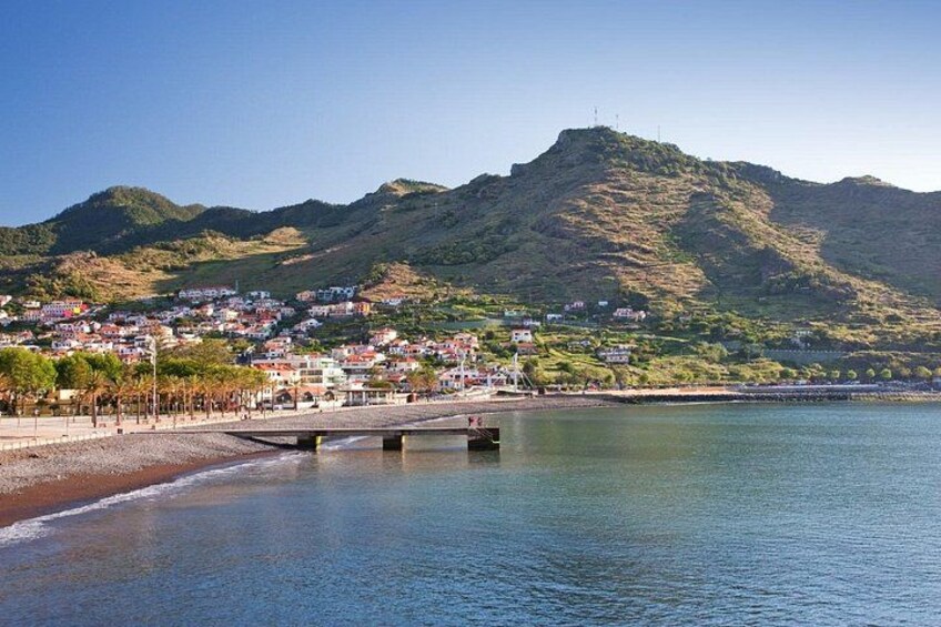 A coastal town with a bridge over water, a beach, and a mountain in the background. 5