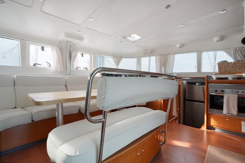 A boat interior with a dining area, a galley with a stove, and a seating arrangement. 3