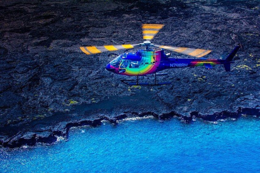 A colorful helicopter flying over a rocky coastline. 4