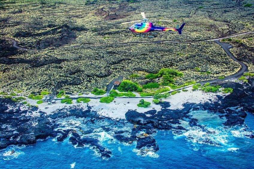 A helicopter over a coastal area with rocky terrain and a small road. 2