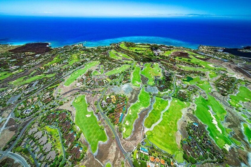 An aerial view of a coastal landscape with green fields, roads, and a coastline. 5