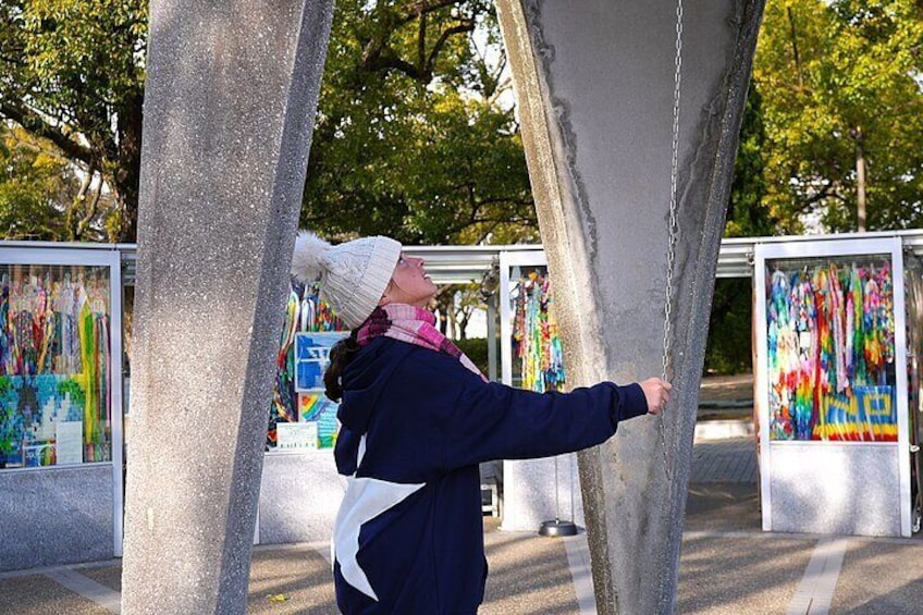 A person leaning against a tree, looking at colorful artwork displayed in a glass case. 1