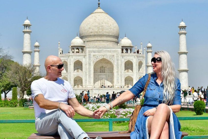 Una coppia seduta su una panchina con il Taj Mahal sullo sfondo. 1