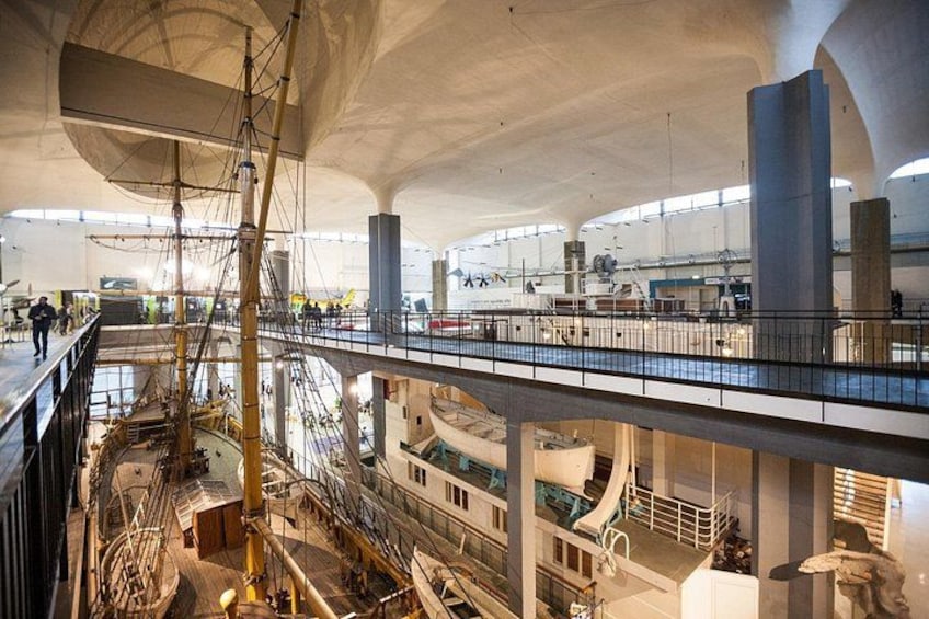 Un vaste espace intérieur à plusieurs niveaux, comprenant notamment un gréement de navire et une maquette de bateau. 1